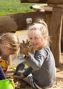 Dos niños juegan alegres en la arena con cubos y juguetes en FarmCamps De Verloren Kost, parque vacacional de Limburg, Países Bajos.