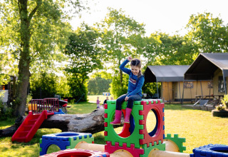 Een kind speelt op kleurrijke speelblokken bij FarmCamps Five Star vakantiepark in Zeeland, Nederland.