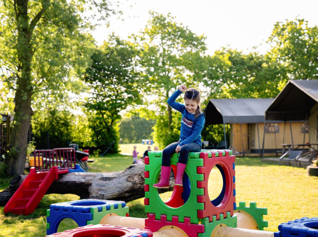 Een kind speelt op kleurrijke speelblokken bij FarmCamps Five Star vakantiepark in Zeeland, Nederland.