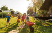 Des enfants jouent avec des brouettes à l’extérieur à FarmCamps Five Star, parc de vacances en Zélande, Pays-Bas.