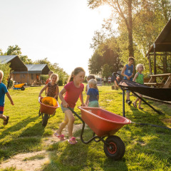 Niños juegan con carretillas en el exterior del parque vacacional FarmCamps Five Star en Zeeland, Países Bajos.