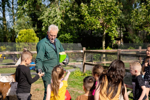 Niños visitan una granja y reciben explicaciones de un granjero en FarmCamps Five Star en Zeeland, Países Bajos.