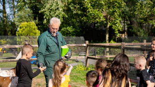 Niños visitan una granja y reciben explicaciones de un granjero en FarmCamps Five Star en Zeeland, Países Bajos.
