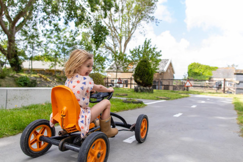 Ein Kind fährt ein Tretfahrzeug auf einem Weg bei FarmCamps Five Star in Zeeland, Niederlande.