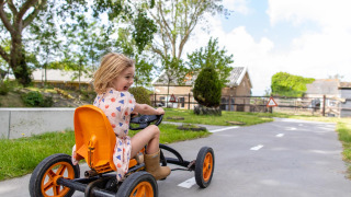 Un niño conduce un coche de pedales en un sendero pavimentado en FarmCamps Five Star, Zeeland, Países Bajos.