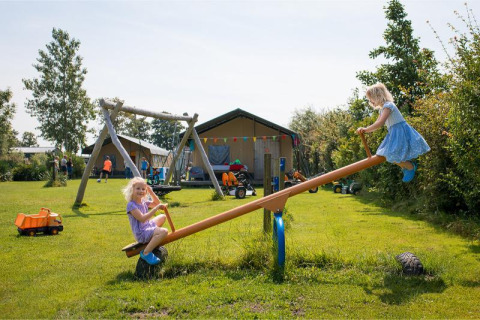 Dos niños juegan en un balancín en FarmCamps Fleur Stables, un parque vacacional en Holanda Septentrional.