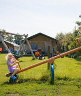 Dos niños juegan en un balancín en FarmCamps Fleur Stables, un parque vacacional en Holanda Septentrional.