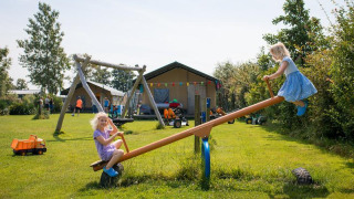 Dos niños juegan en un balancín en FarmCamps Fleur Stables, un parque vacacional en Holanda Septentrional.