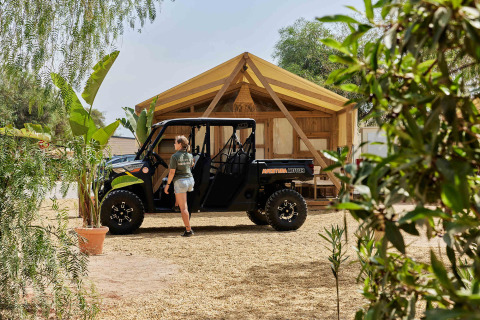 Eine Person steht neben einem Geländewagen vor einer Hütte im TAIGA Almeria Playa, Andalusien, Spanien.