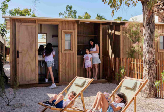 Kinder und Erwachsene entspannen vor Holzhütten im TAIGA Almeria Playa Ferienpark in Andalusien, Spanien.