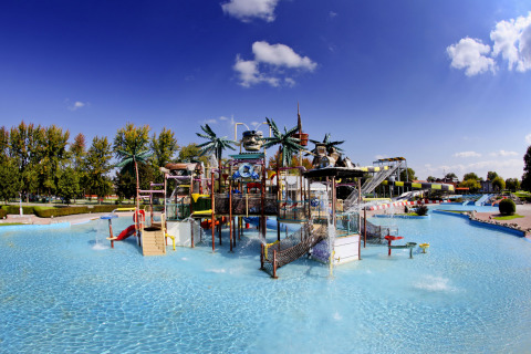 Water park at Camping Terme Catez featuring slides, palm trees, and a shallow pool under a clear blue sky.