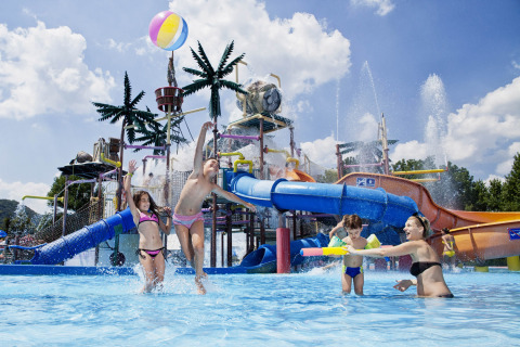 Kids and adults play in a water park with slides and fountains at Camping Terme Čatež holiday park, Slovenia.