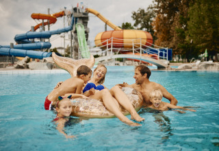 Familie nyder en sjov dag i poolen på Camping Terme Catez feriepark med vandrutsjebaner i baggrunden.