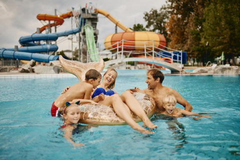 Famiglia che si diverte in piscina al Camping Terme Catez, parco vacanze con scivoli in Slovenia.