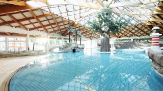 Piscina cubierta con decoración tropical y techo de madera en Camping Terme Čatež en Eslovenia.