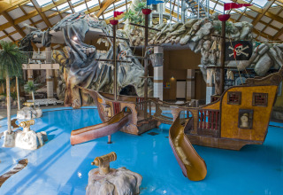 Indoor water park at Camping Terme Catez, Slovenia, featuring a pirate ship, slides and rocky décor.