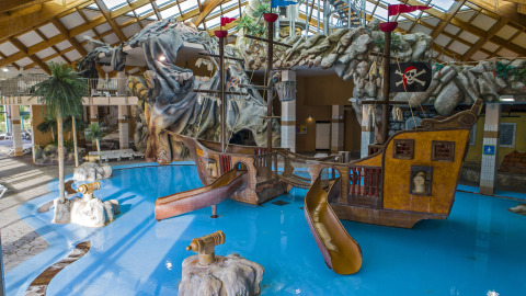 Parque acuático cubierto en Camping Terme Catez, Eslovenia, con barco pirata, toboganes y rocas.