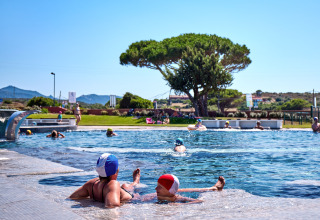 Des vacanciers se détendent dans la piscine du Camping Village Baia Blu La Tortuga en Sardaigne, Italie.