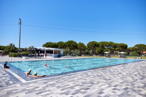 Außenpool mit Gästen unter blauem Himmel und Bäumen im Camping Village Baia Blu La Tortuga, Sardinien, Italien.