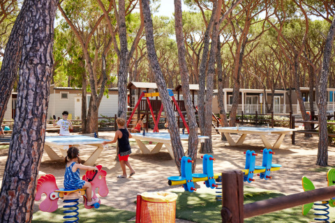 Bambini giocano nell’area giochi e adulti al ping pong al Camping Village Baia Blu La Tortuga in Sardegna, Italia.