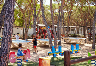Bambini giocano nell’area giochi e adulti al ping pong al Camping Village Baia Blu La Tortuga in Sardegna, Italia.