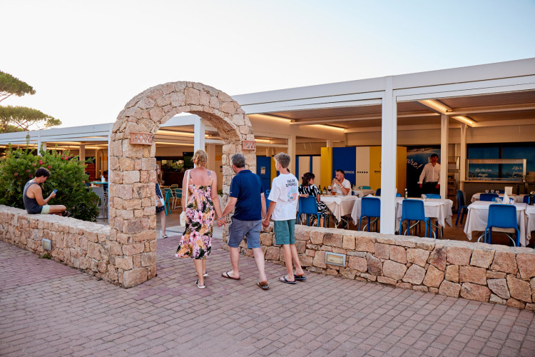 Des clients entrent par une arche en pierre au restaurant du Camping Village Baia Blu La Tortuga en Sardaigne, Italie.