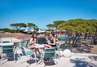Two women enjoy ice cream on a terrace overlooking Camping Village Baia Blu La Tortuga in Sardinia, Italy.