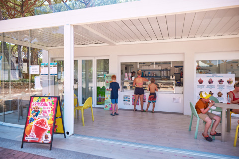 Niños y adultos compran helado en una heladería al aire libre en Camping Village Baia Blu La Tortuga, Cerdeña.