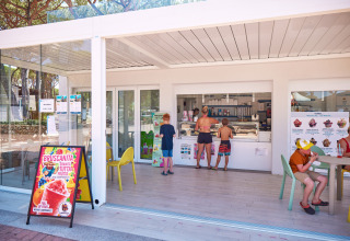 Kinder und Erwachsene kaufen Eis in einem offenen Eiscafé im Camping Village Baia Blu La Tortuga, Sardinien.