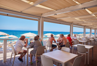 Outdoor restaurant at Camping Village Baia Blu La Tortuga overlooking the beach and blue sea in Sardinia, Italy.