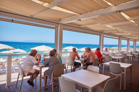 Outdoor restaurant at Camping Village Baia Blu La Tortuga overlooking the beach and blue sea in Sardinia, Italy.