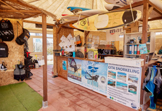 Vandaktivitetsudstyrsbutik på Camping Village Baia Blu La Tortuga i Sardinien med surfbrætter og dykkerudstyr.