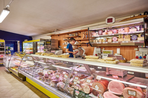 Deli counter at Camping Village Baia Blu La Tortuga in Sardinia, showcasing cheese and cured meats.