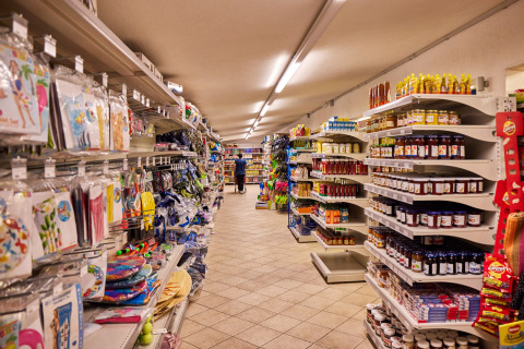 Corsia del minimarket al Camping Village Baia Blu La Tortuga con scaffali pieni di cibo e articoli vari.