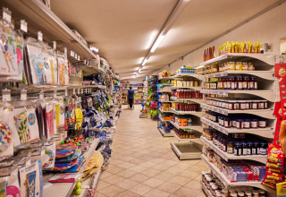 Aisle in the Camping Village Baia Blu La Tortuga shop, shelves stocked with groceries and park goods.