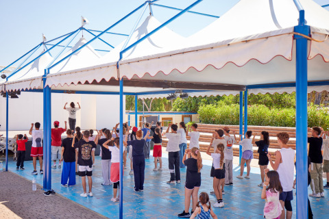 Clase de baile para niños y adultos bajo pérgolas en Camping Village Baia Blu La Tortuga, Cerdeña, Italia.