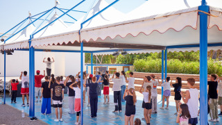 Clase de baile para niños y adultos bajo pérgolas en Camping Village Baia Blu La Tortuga, Cerdeña, Italia.