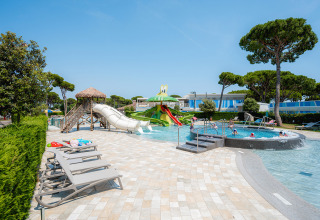 Udendørs swimmingpool og vandlegeplads med rutsjebaner og liggestole på Camping Village Cavallino i Veneto, Italien.