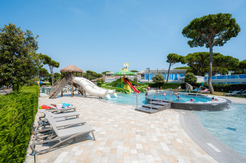 Udendørs swimmingpool og vandlegeplads med rutsjebaner og liggestole på Camping Village Cavallino i Veneto, Italien.
