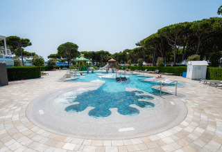 Udendørs swimmingpool-område med liggestole og træer på Camping Village Cavallino i Veneto, Italien.