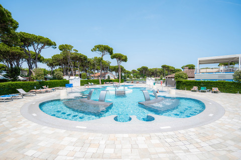 Piscina moderna con chorros de agua y tumbonas en el Camping Village Cavallino en Véneto, Italia.
