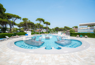 Moderne zwembad met massagestralen en ligstoelen bij Camping Village Cavallino vakantiepark in Veneto, Italië.