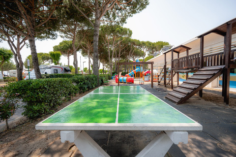 Camping Village Cavallino: Tafeltennistafel, speeltuin, bomen en chalets in een vakantiepark in Veneto, Italië.