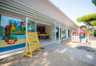 Buiten speelplaats voor kinderen bij Camping Village Cavallino in Veneto, Italië, met speelhuisje en zand.