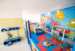 Binnen-speelruimte met kleurrijke ballenbak en zee-muurschildering bij Camping Village Cavallino, Veneto, Italië.