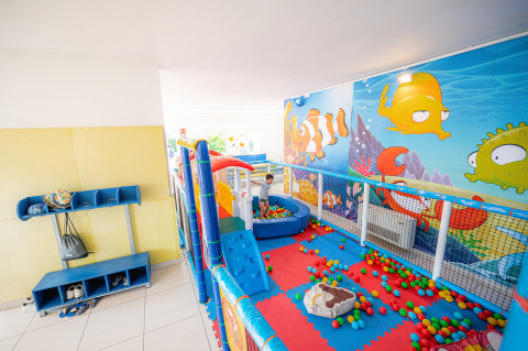 Indoor speelzone met kleurrijke ballenbak en zeemuur bij Camping Village Cavallino, Veneto, Italië.