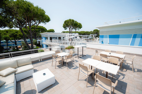 Dakterras met tafels, stoelen en lounge bij Camping Village Cavallino, Veneto, Italië in de zomer.