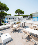 Terraza con mesas, sillas y áreas lounge en Camping Village Cavallino, Veneto, Italia bajo el sol.