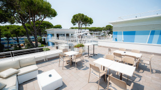 Terraza con mesas, sillas y áreas lounge en Camping Village Cavallino, Veneto, Italia bajo el sol.