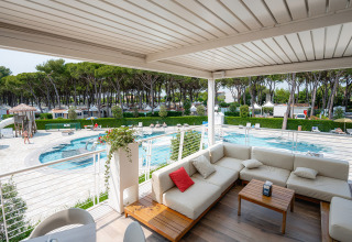 Vista dalla terrazza coperta con salotto sulla piscina al Camping Village Cavallino, Veneto, Italia.